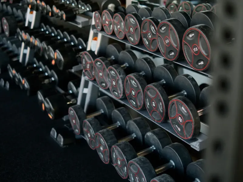 Rek met dumbbells in de trainingsruimte (voorbeeldfoto)
