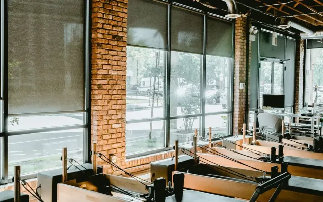 Ruime studio met reformers bij grote ramen (voorbeeldfoto)